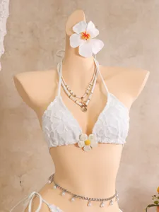 Detailansicht des weißen Bikinis mit Blumenstickerei und Strand-Accessoires