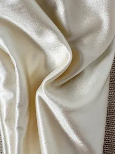 Detaillierte Nahaufnahme der glänzenden metallischen Bikini-Stofftextur in Creme-Gold