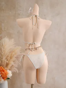 Vue arrière détaillée d'un bikini au crochet avec chaîne de taille à breloques coquillages.