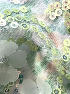 Macro de elegante tela de malla verde claro decorada con lentejuelas y flores textiles