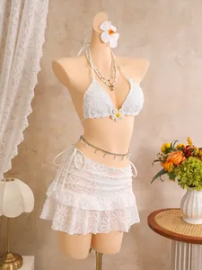 Exquisite Detailansicht des weißen dreiteiligen Bikini-Sets mit Blumenstickerei und Rock.