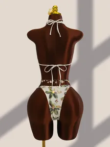 Détail d'un bikini en résille brodé de fleurs avec chaîne de taille en coquillages