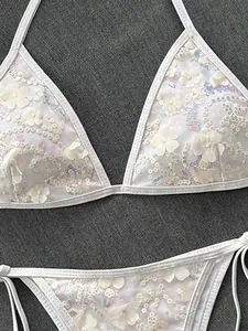 Detalle de un bikini de malla blanca con aplicaciones florales y lentejuelas