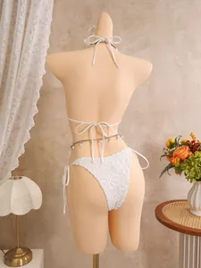 Detailansicht des weißen Bikinis mit Blumenstickerei und elegantem Bindedesign am Rücken