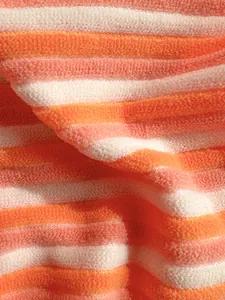 Vista macro que muestra la suave textura de rizo de la tela de bikini a rayas naranja y melocotón