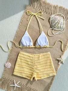 Gros plan d'un bikini deux pièces jaune avec short texturé sur un tapis de plage.
