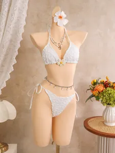Weißer Bikini mit Blumenstickerei auf Schaufensterpuppe mit Strandzubehör im Detail