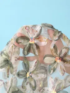 Vue détaillée de broderies florales et de paillettes sur un tissu en maille transparente.