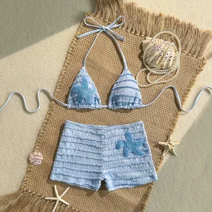 Vue détaillée d'un bikini bleu clair deux pièces avec étoiles de mer et short sur tapis