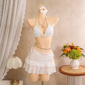 Detailansicht eines weißen dreiteiligen Bikinisets mit Blumenstickerei und Spitzenrock