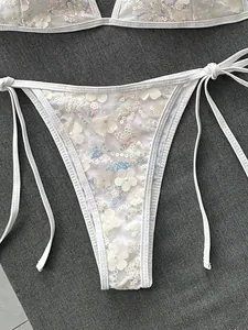 Primer plano de braguita de bikini blanca con lentejuelas y flores en 3D de malla