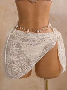Detail van een crèmekleurige kanten rok met decoratieve schelp- en zeester-tailleketting
