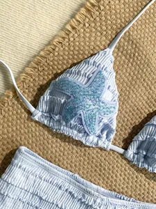 Détail du haut de bikini bleu avec applique d'étoile de mer et paillettes scintillantes