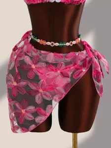 Détail de la broderie florale rose et des paillettes sur le paréo en maille pour bikini