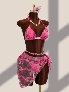Gros plan détaillé d'un ensemble bikini brodé de fleurs roses avec paréo en mesh assorti