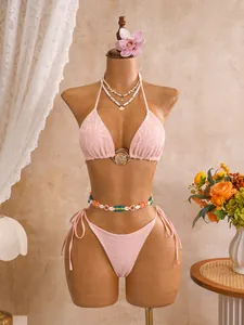 Detailweergave van een roze kanten bikini met opengewerkt patroon op een mannequin.