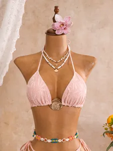 Gedetailleerd overzicht van roze kanten bikini-top met een decoratieve gouden ring centraal