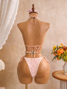 Gedetailleerd achteraanzicht van de roze kanten bikini set met een schelpen taille ketting