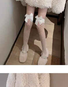Detail view of white fishnet over-the-knee socks with decorative bows in Lolita style.