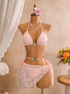 Detail van een roze driedelige kantbikini met een opengewerkte omslagrok op een paspop