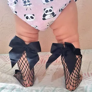 Detailed view of girls' black fishnet socks with large satin bows on a toddler