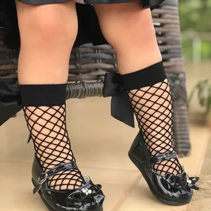 Close-up detail of girls black fishnet socks with decorative large ribbon bow tie