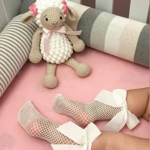 Close-up detail of white fishnet socks for girls featuring large decorative silk bows