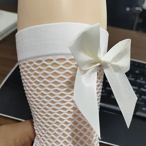 Detailed view of white girl's fishnet sock featuring a large white satin bow decoration
