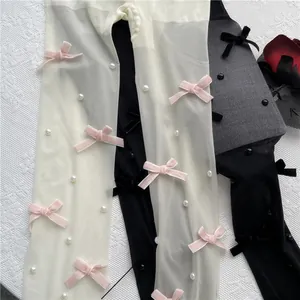 Detailaufnahme von Lolita Strumpfhosen in Weiß und Schwarz mit Schleifen und Perlen