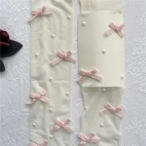 Detailansicht weißer Lolita-Strümpfe mit rosa Samtschleifen und Perlenverzierungen