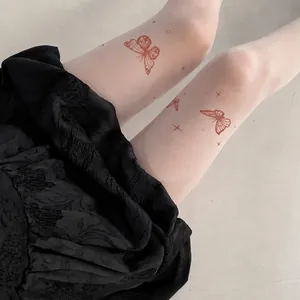 Close-up view of white tattoo tights featuring elegant red butterfly prints and stars.