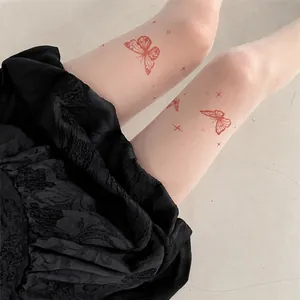 Gros plan de collants tatoués blancs avec d'élégants motifs de papillons rouges et d'étoiles.
