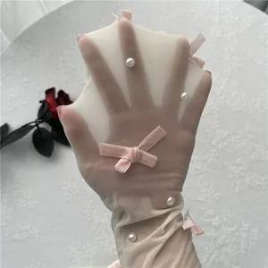 Detailaufnahme weißer transparenter Strümpfe mit Perlen und rosa Samtschleifen