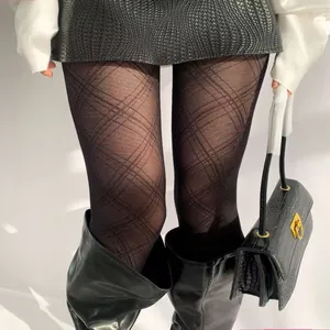 Close-up of black diamond pattern pantyhose paired with stylish black leather boots