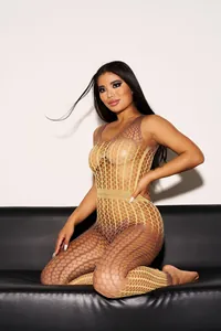 Asiatisches Model in einem sexy gelben Batik-Netzbody auf einem schwarzen Sofa
