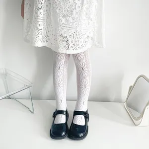 Close-up view of white floral jacquard mesh tights for girls in minimalist white setting