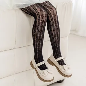 Close-up of girls black mesh tights with heart pattern and cream Mary Jane shoes