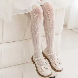 Close-up detail of white heart pattern lace mesh tights for girls with elegant shoes