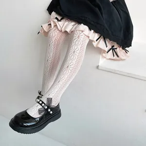 Detail view of girls' white floral lace tights paired with pearl Mary Jane shoes