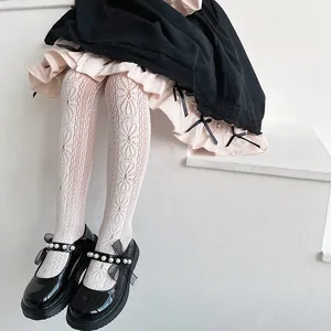 Close-up of girl's white lace tights with floral heart pattern in princess style