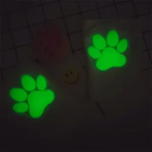 Close-up macro view showing the bright green luminous cat paw pads glowing in the dark.