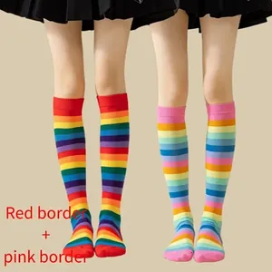 Detail view of rainbow striped over-the-knee socks with red and pink borders shown on models