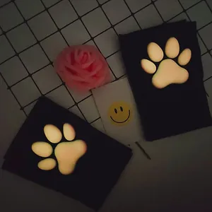Close-up view of luminous 3D silicone cat paw pads on black velvet over-the-knee socks.
