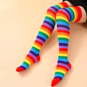 Close-up of vibrant rainbow striped over-the-knee socks on model legs.