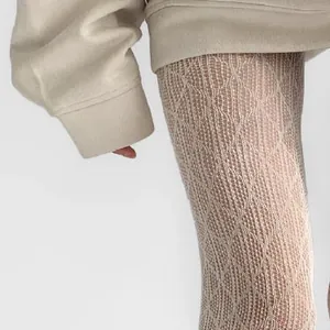 Close-up detail of cream hollow lace stockings featuring a textured diamond lattice pattern