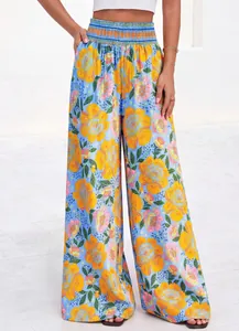 Détail du pantalon à jambes larges et taille haute avec imprimé floral jaune vif.