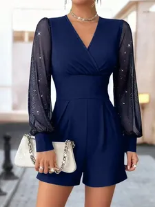 Detail des dunkelblauen V-Ausschnitt-Jumpsuits mit eleganten Mesh-Ärmeln und Glitzereffekt