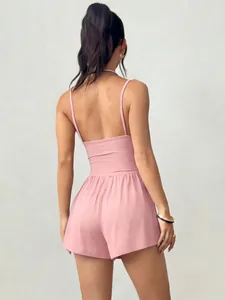Back view of a casual pink strappy romper with open back and waist-cinching shorts.