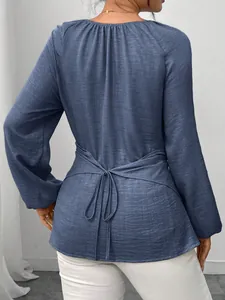 Rückenansicht des blauen gewebten Langarmshirts mit Bindegürtel und unregelmäßigem Saum