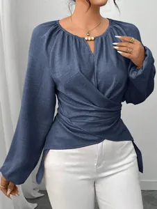 Detailaufnahme der blauen Damenbluse mit Wickeloptik an der Taille und Laternenärmeln